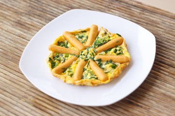 Omelette with sausages and herbs on white plate
