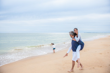 Family in casual clothes playing at the beach