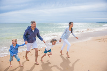 A four people family is playing in the sea waves