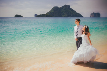 Fototapeta na wymiar bride embrace groom walking along sandy beach