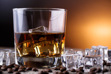 Glass of whiskey with ice and coffee beans.