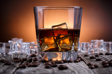 Glass of whiskey with ice and coffee beans.