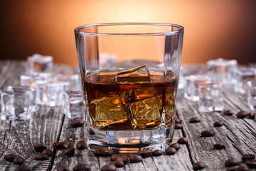 Glass of whiskey with ice and coffee beans.