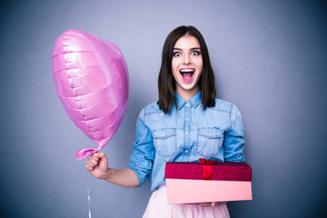 Amazed woman holding balloon and gift box
