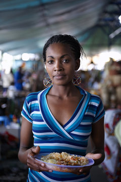 Young woman, eating while working at a street market in Nairobi