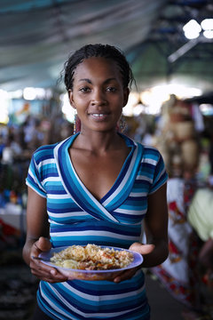 Young woman, eating while working at a street market in Nairobi