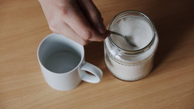 man pours sugar and brew a cup of tea