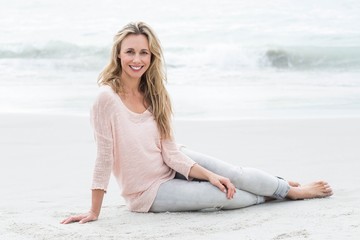 Smiling pretty blonde relaxing on the sand