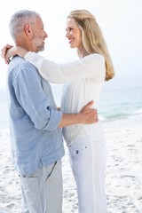 Happy couple smiling at each other by the sea