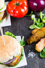 Homemade burger with vegetables on wooden table