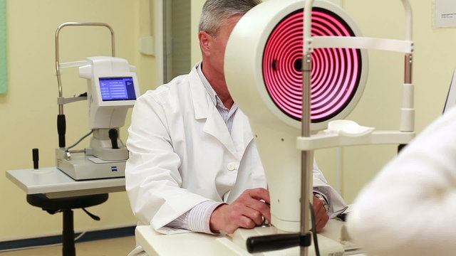 Young woman having her eyes examined by an eye handsome elderly