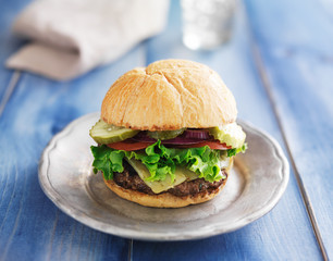 gourmet cheeseburger on rustic painted planks
