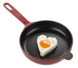 Heart shaped egg on cast iron cookware close-up.