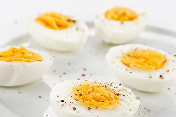 Soft boiled egg with black pepper in white plate close-up.