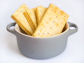 Stack of butter crackers in bowl on white background
