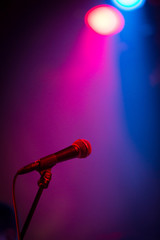 Obraz premium A band stage microphone highlighted by a pink and blue light
