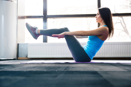 Happy young woman doing exercise on yoga mat