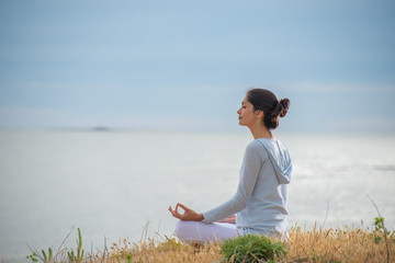 Woman meditating face to the ocean