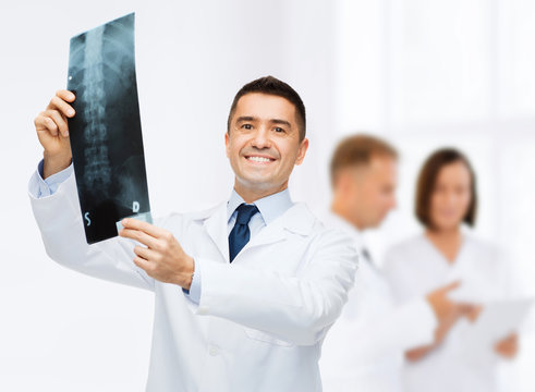 smiling male doctor holding x-ray at hospital