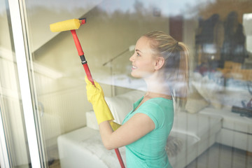 happy woman in gloves cleaning window with sponge