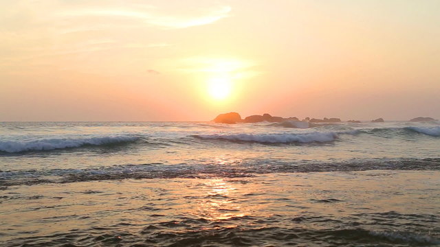 Ocean view in Hikkaduwa in sunset with waves splashing the beach.