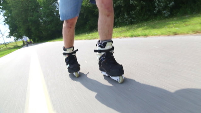 Young man rollerblading in park on a beautiful day, feet going backwards