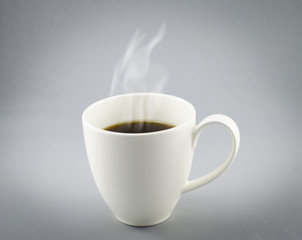 Cup of hot coffee with steam on gray background
