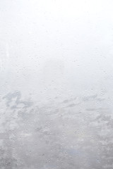 Blur City behind building glass window with rain water drops