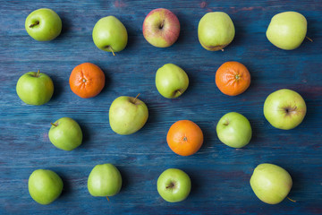 Apples and oranges on old wooden background