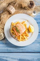 Tasty salmon with chips served on plate with lemon