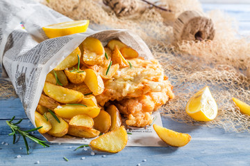 Tasty fish and chips served in paper with lemon