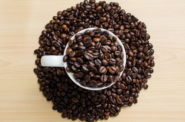 Roasted brown coffee beans & mug  on wooden table