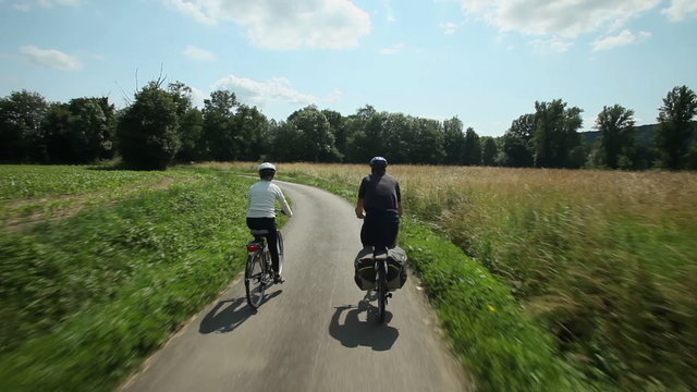 Slow motion - Retired couple cycling on road in village in France