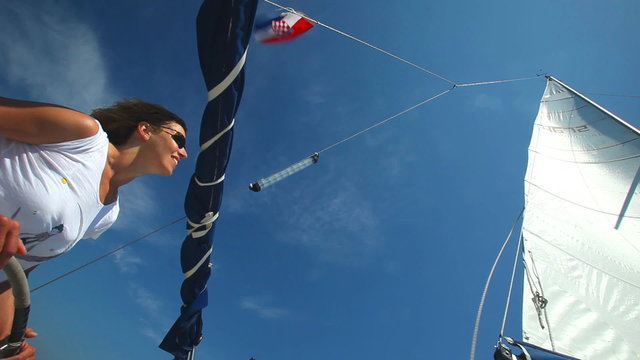 Woman at helm of boat looking at wind in sail