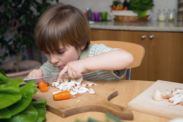 Left-Handed Boy Cutting Carrot on a Wooden Board Carefully