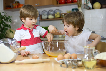 Boy Licking Whisk While His Brother Mixing Eggs in Mixing Bowl