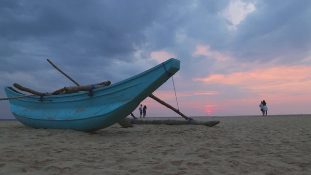 HIKKADUWA, SRI LANKA - FEBRUARY 2014: Boat on Hikkaduwa beach at sunset with people taking pictures. Hikkaduwa is famous for its beautiful beaches. 