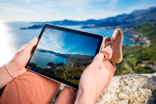 Holding digital tablet on the mountain