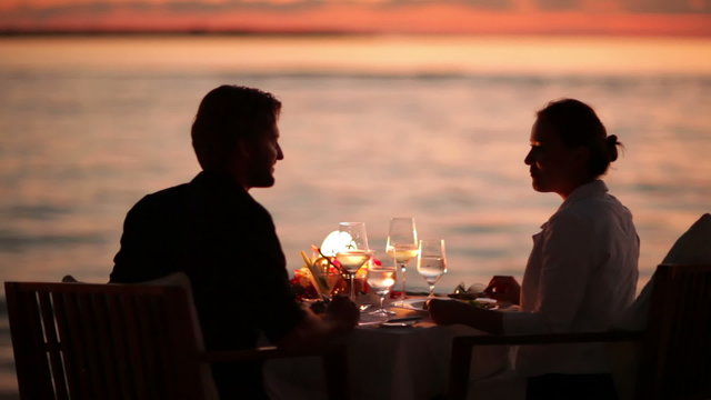 couple dining on beach at sunset