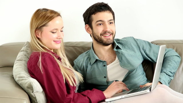 Young couple sitting on couch on laptop at home