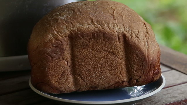 european man hands put warm fresh brown bread on plate	