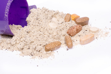 Whey protein powder in scoop with vitamins and plastic shaker on