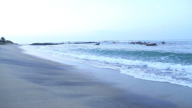 View of waves and fishermen in Mirissa. These traditional fishermen find it harder to make a living from poor fishing catches.