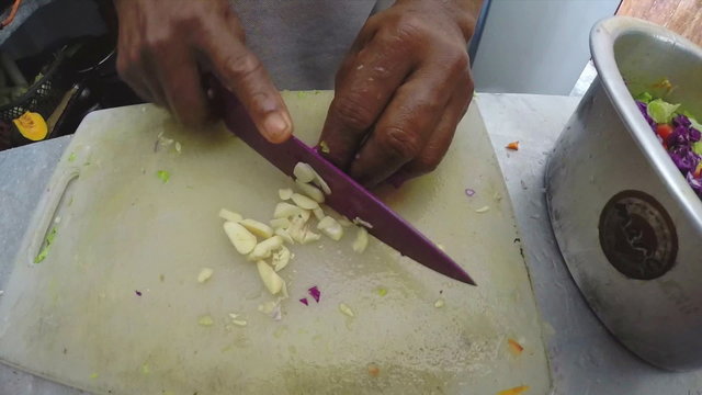 Slow motion of man slicing garlic in the kitchen. 