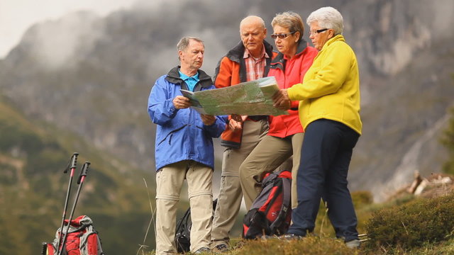 four senior hikers looking at map close