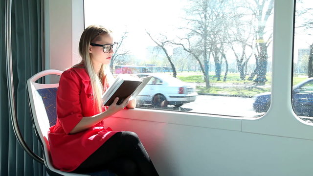 Beautiful blond woman reading book while riding tram