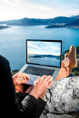 Man with laptop on the top of mountain