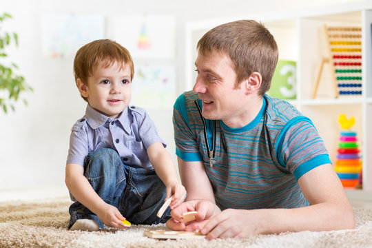 Child boy and father play with puzzle toy