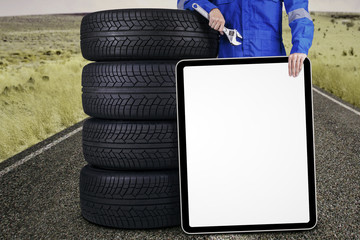 Mechanic with tires and a board outdoors