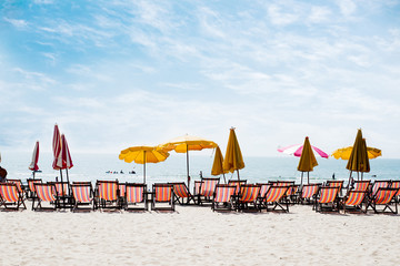 Beach chairs on the white sand beach with cloudy blue sky